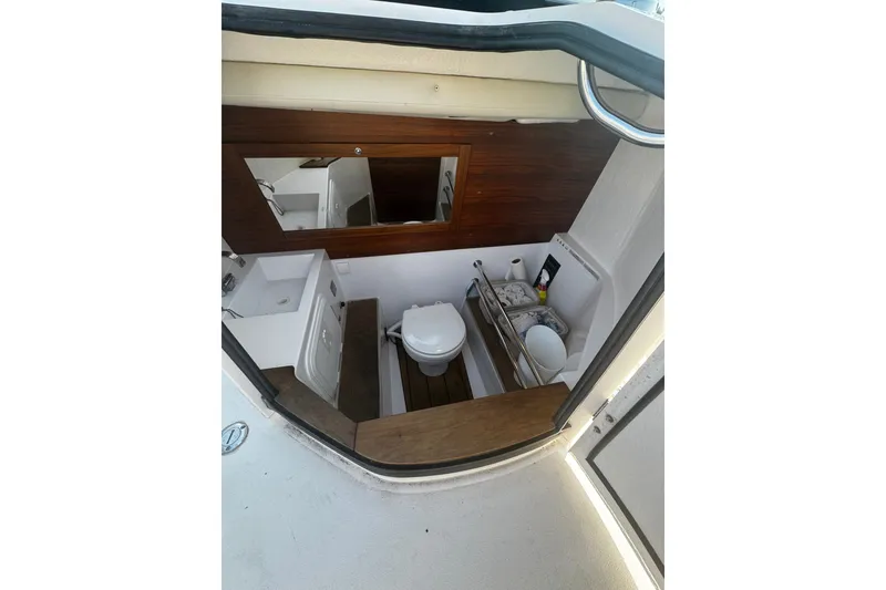 Slide: The Image of 2016 Axopar 28 Cabin interior bathroom with toilet, sink, and wooden accents. - 10