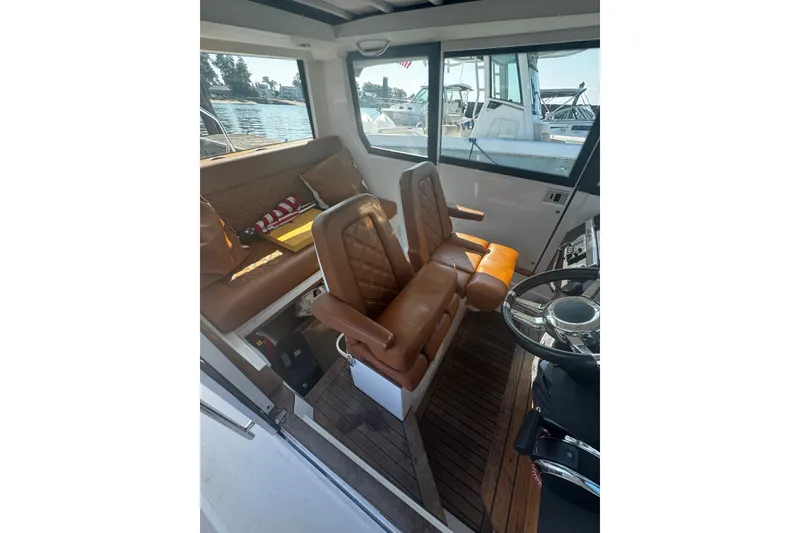 Slide: The Image of Interior of 2016 Axopar 28 Cabin boat with brown leather seating and steering wheel. - 8