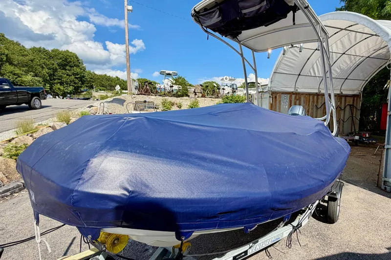 Slide: The Image of 2023 AB Inflatables Nautilus 14 DLX boat covered with blue tarp, parked outdoors. - 2