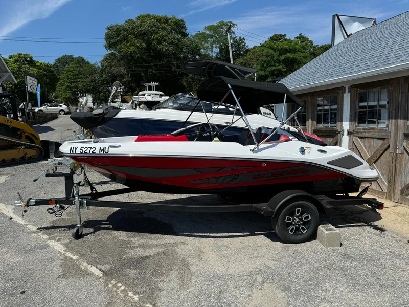 The Image of 2025 Scarab 165 ID boat on trailer, parked outdoors near a building. - 1