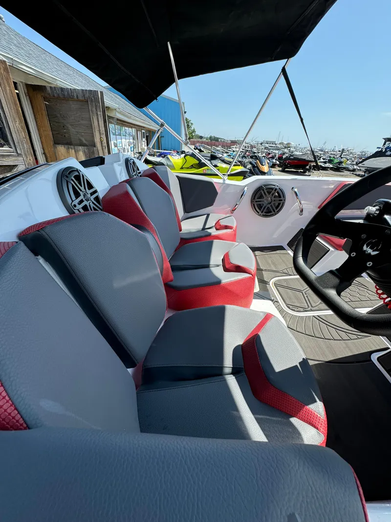 Slide: The Image of 2025 Scarab 165 ID boat interior with red and gray seating, steering wheel, and speakers. - 21