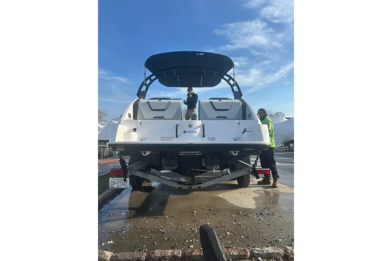 Slide: The Image of 2025 Yamaha Boats AR220 on trailer, rear view, with two people nearby under clear sky. - 5