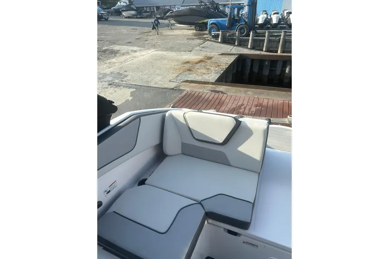 Slide: The Image of 2025 Yamaha Boats AR220 interior seating with modern design at a marina. - 7
