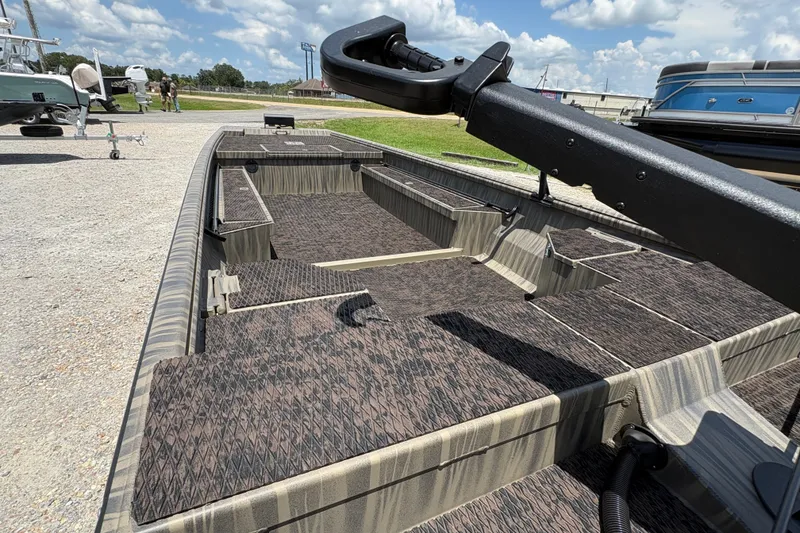 Slide: The Image of 2027 Gator Tail 1860 boat with textured flooring, parked outdoors under a blue sky. - 7