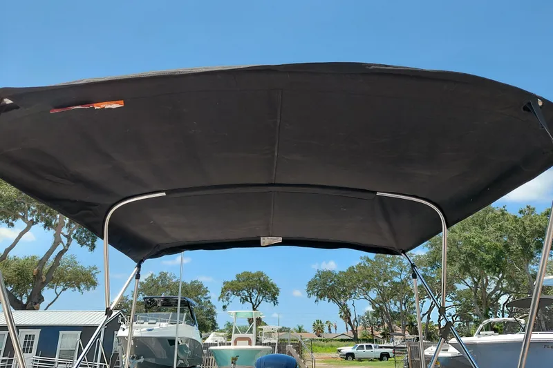 Slide: The Image of 2022 Bayliner Element E18 boat with black canopy under clear blue sky. - 31