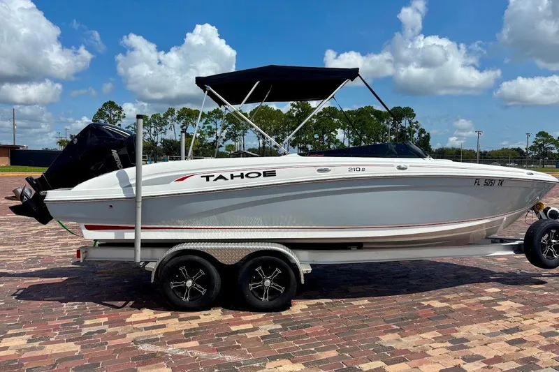 Slide: The Image of 2023 Tahoe 210 S Limited boat on trailer, parked on brick pavement under blue sky. - 23