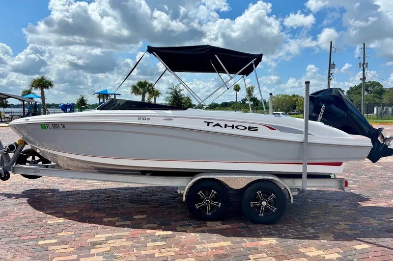 Slide: The Image of 2023 Tahoe 210 S Limited boat on trailer, parked outdoors under a cloudy sky. - 22