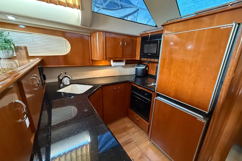 Slide: The Image of Luxurious kitchen interior of 2003 Carver 466 Motor Yacht with wood cabinetry and modern appliances. - 27