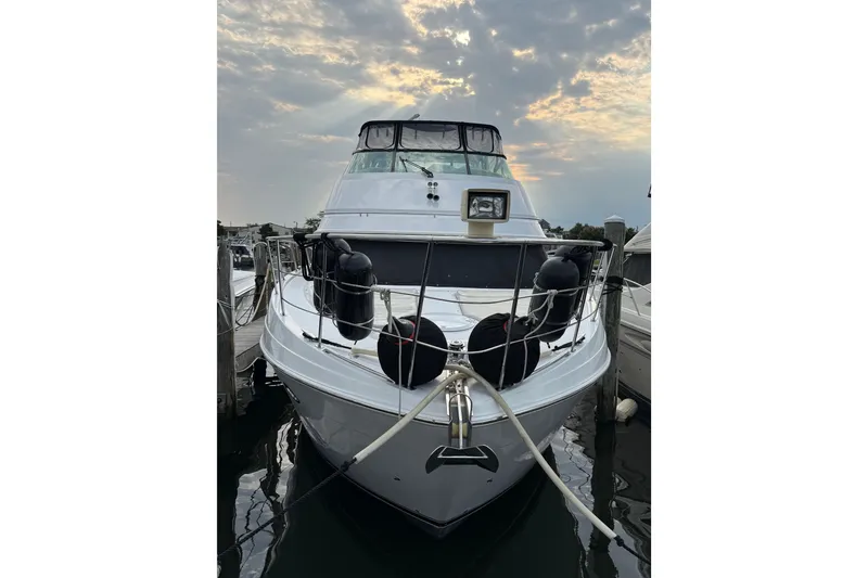 Slide: The Image of 2003 Carver 466 Motor Yacht docked at sunset, showcasing sleek design and spacious deck. - 5