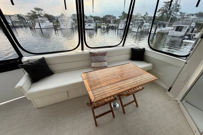 Slide: The Image of 2003 Carver 466 Motor Yacht interior with elegant seating and wooden table, overlooking marina. - 10
