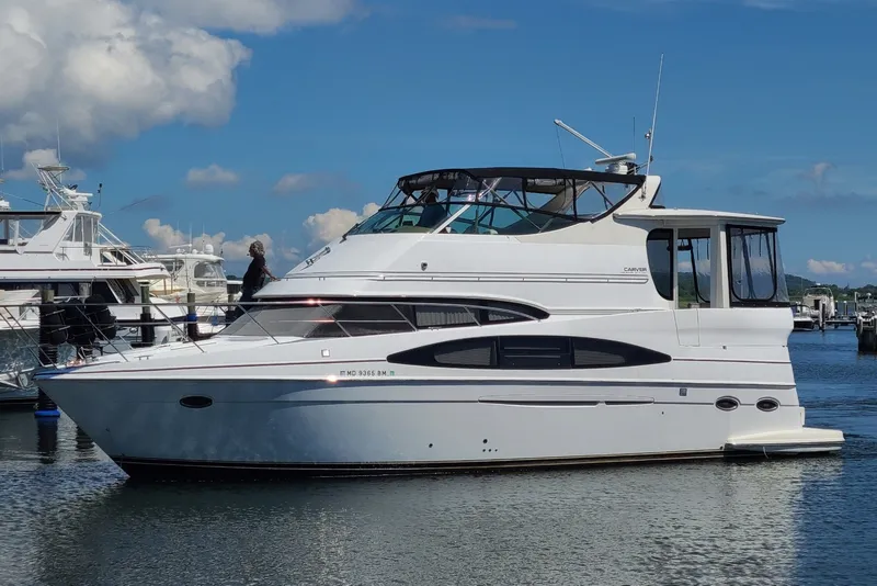 Slide: The Image of 2003 Carver 466 Motor Yacht docked in a marina under a clear blue sky. - 1