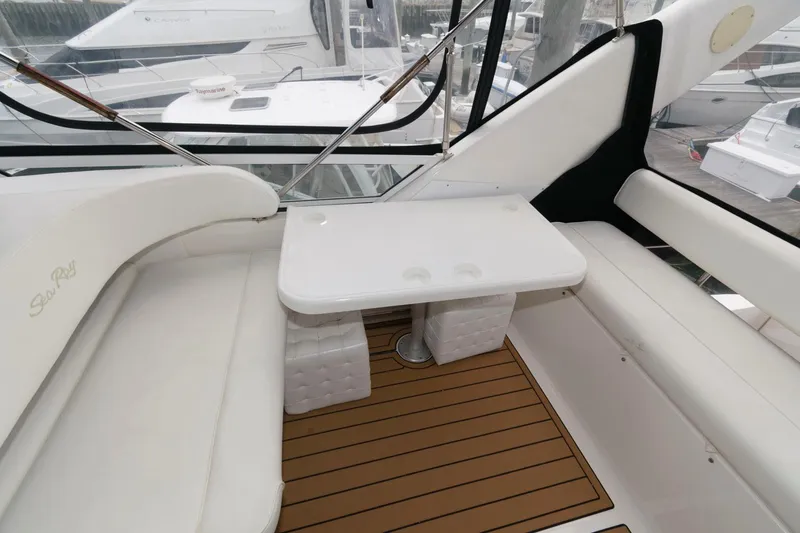 Slide: The Image of 2001 Sea Ray 450 Express Bridge interior seating area with table and white cushions. - 11
