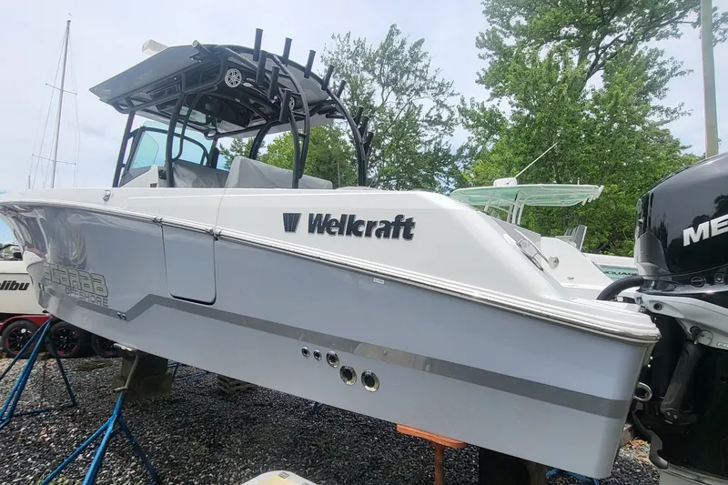 Slide: The Image of 2023 Wellcraft 302 Fisherman boat displayed outdoors with trees in the background. - 4