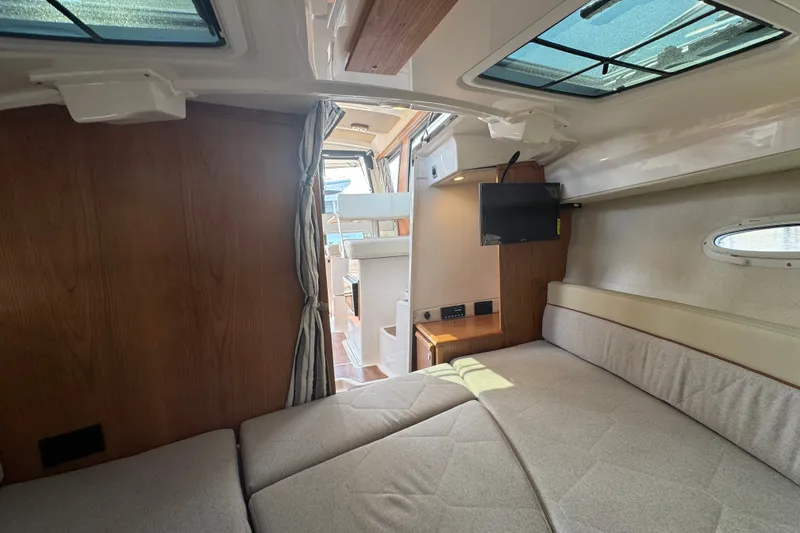 Slide: The Image of 2027 Cutwater C-248 Coupe interior cabin with bed, TV, and wood accents. - 13