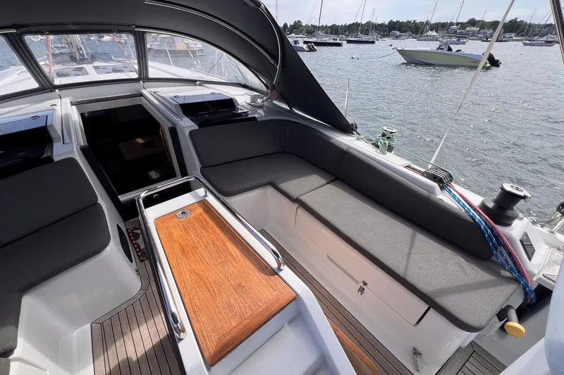 Slide: The Image of 2020 Hanse 458 yacht cockpit with cushioned seating and wooden table, docked in a marina. - 36