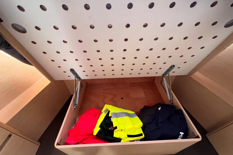 Slide: The Image of Open storage compartment in 2020 Hanse 458 yacht with clothing inside. - 59