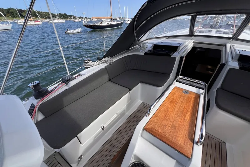 Slide: The Image of 2020 Hanse 458 yacht cockpit with comfortable seating and wooden table, docked in a marina. - 37