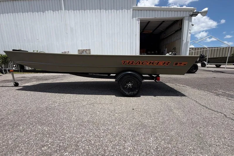 The Image of 2027 Tracker Grizzly 15 Jon boat on trailer, parked outside a warehouse. - 0