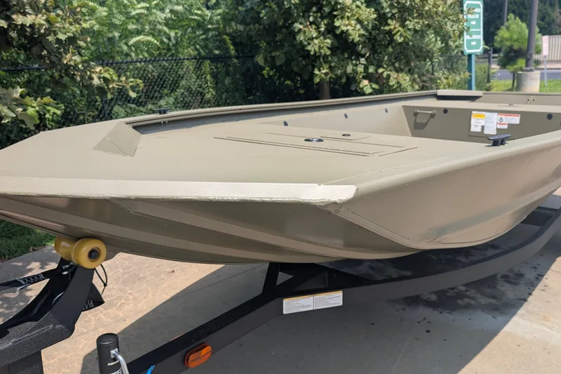 The Image of 2027 Tracker Grizzly 1648 Utility boat on trailer, outdoors in sunny setting. - 0