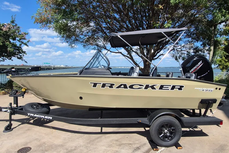 The Image of 2027 Tracker Pro Guide V-175 Combo boat on trailer, parked near a scenic waterfront. - 0