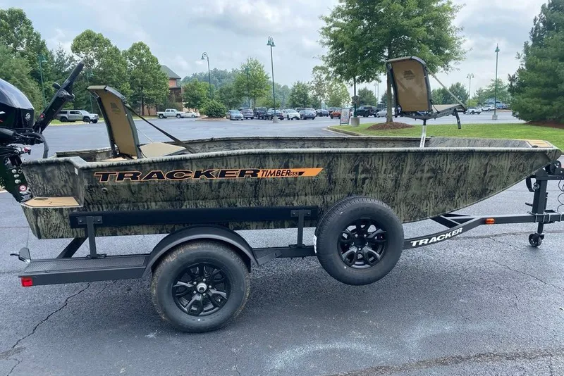 The Image of 2027 Tracker Grizzly 1553 Timber boat on trailer in parking lot, camo design. - 0