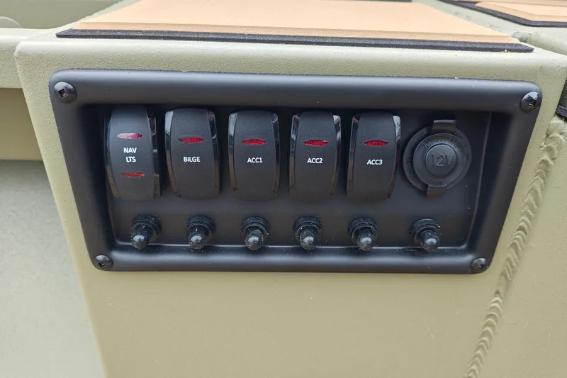 Slide: The Image of Control panel of 2027 Tracker Grizzly 1553 Timber with switches and 12V outlet. - 18