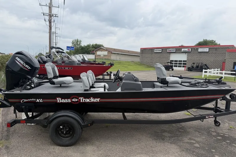 The Image of 2027 Tracker Bass Tracker Classic XL boat on trailer, parked near dealership. - 0