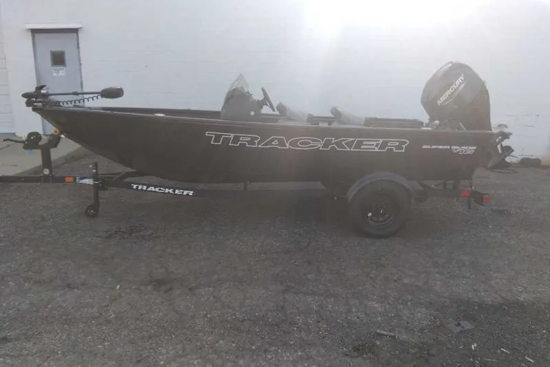 The Image of 2027 Tracker Super Guide V-16 SC boat on trailer, parked outdoors. - 0