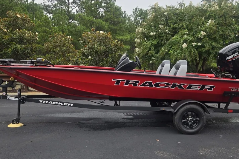 The Image of 2027 Tracker Pro Team 175 boat in vibrant red on trailer, surrounded by greenery. - 0