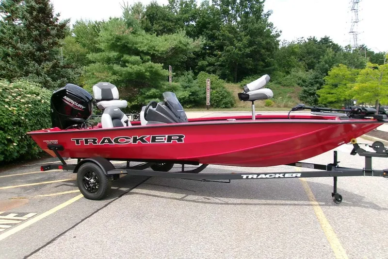 The Image of 2027 Tracker Pro Team 175 boat on trailer in parking lot, surrounded by greenery. - 0