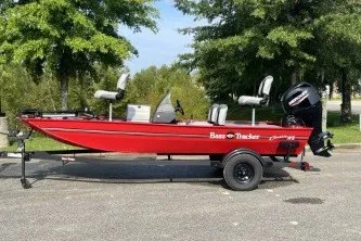 The Image of Red 2027 Bass Tracker Classic XL on a trailer, featuring an outboard motor and three seats. - 0