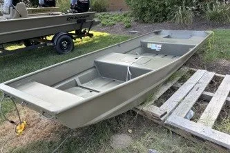 The Image of 2027 Tracker Grizzly 15 Jon boat on grass, near wooden pallets. - 0