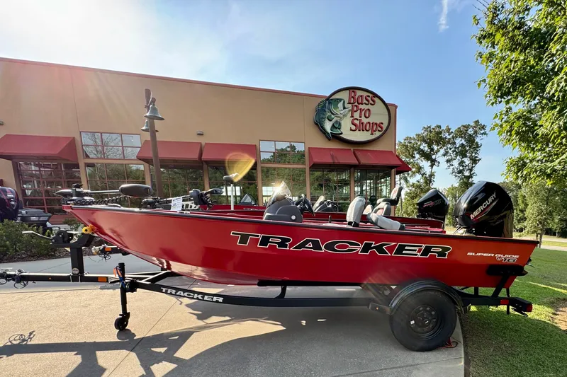 The Image of Red 2027 Tracker Super Guide V-16 SC boat outside Bass Pro Shops on a sunny day. - 0