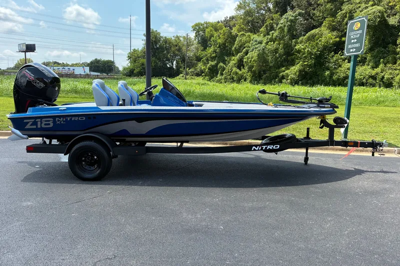 The Image of 2027 Nitro Z18 XL boat on trailer, parked near green landscape under blue sky. - 0