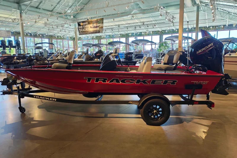 The Image of 2027 Tracker Pro Team 175 boat in showroom, red exterior, Mercury engine, on trailer. - 1