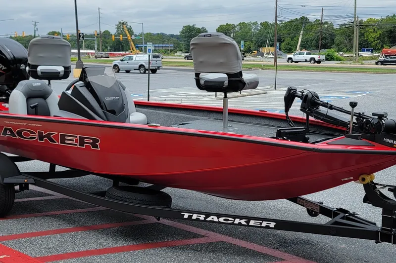 The Image of 2027 Tracker Pro Team 175 boat in parking lot, red exterior, equipped with fishing seats. - 0