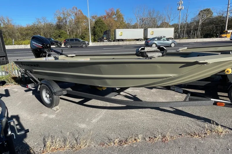 The Image of 2027 Tracker Grizzly 1654 T Sportsman boat on trailer, parked near a busy road. - 0
