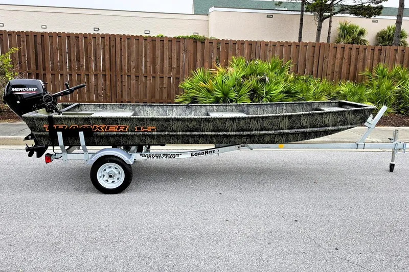 The Image of 2027 Tracker Grizzly 15 Jon boat on trailer, featuring Mercury outboard motor. - 0