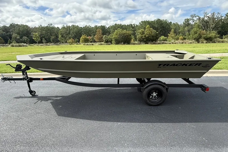 The Image of 2027 Tracker Grizzly 1648 Utility boat on trailer, parked on asphalt with grassy background. - 0