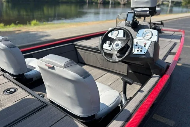Slide: The Image of 2027 Tracker Pro 170 boat interior with steering console and seating by a lake. - 17