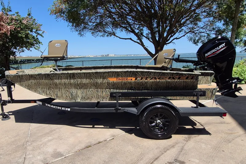 The Image of 2027 Tracker Grizzly 1553 Timber boat on trailer, camo design, Mercury outboard motor. - 0