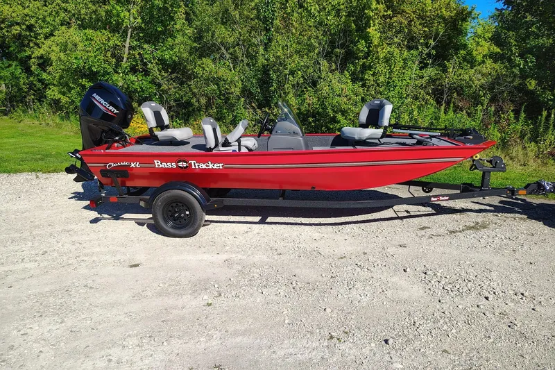 The Image of Red 2027 Tracker Bass Tracker Classic XL boat on a trailer, parked outdoors. - 0