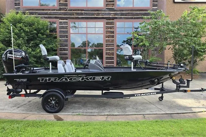 The Image of 2027 Tracker Pro Team 175 boat on trailer, parked outdoors near building. - 0