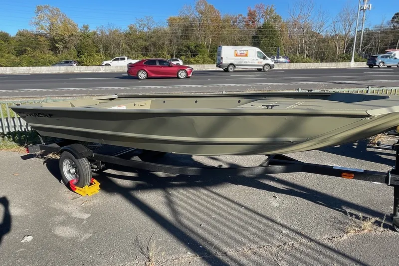 The Image of 2027 Tracker Grizzly 1648 Utility boat on trailer, parked near highway. - 0
