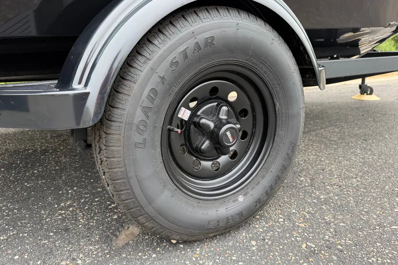 Slide: The Image of Trailer tire of 2027 Tracker Super Guide V-16 SC on asphalt surface. - 19