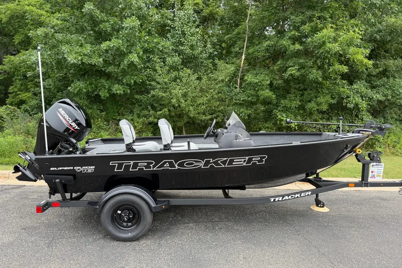 The Image of 2027 Tracker Super Guide V-16 SC fishing boat on trailer, parked outdoors. - 0