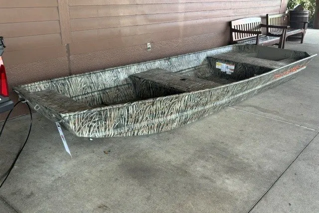 The Image of 2027 Tracker Grizzly 15 Jon boat with camouflage design on concrete surface. - 0
