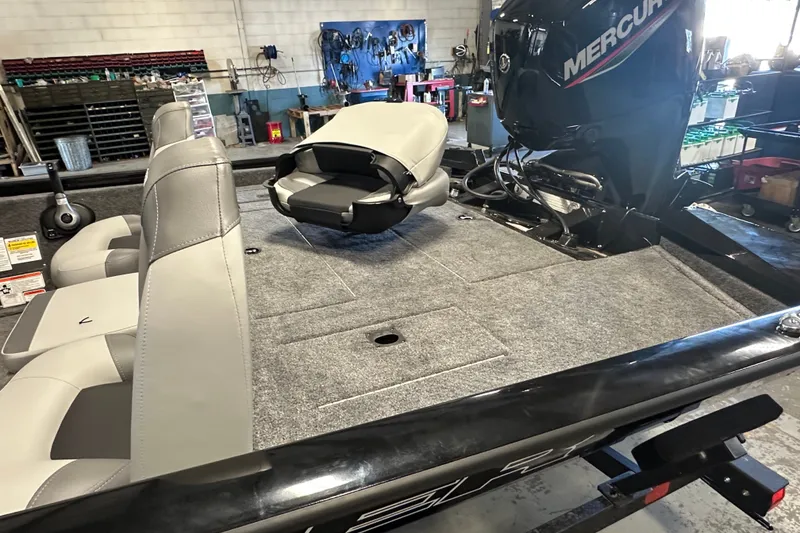 Slide: The Image of 2027 Tracker Pro Team 175 boat interior with seating and Mercury engine in workshop. - 13
