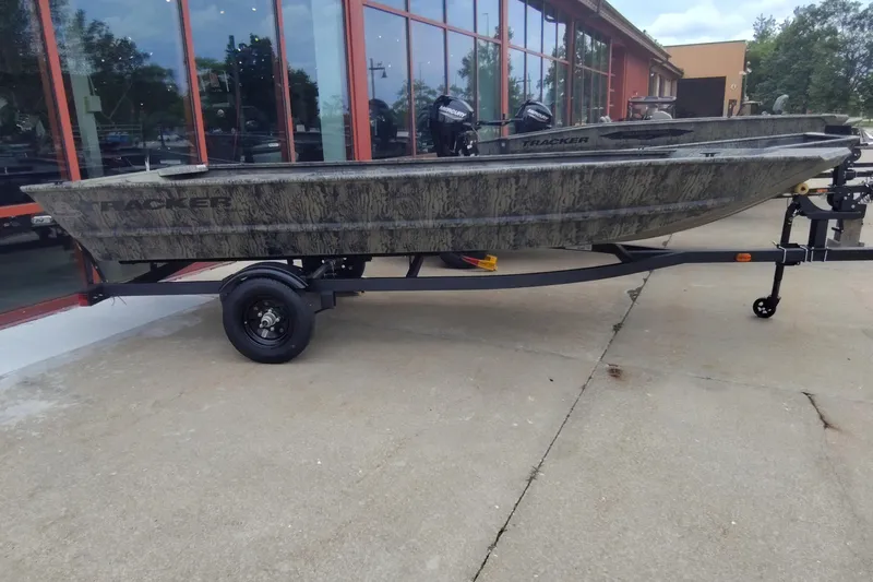 The Image of 2027 Tracker Grizzly 1648 Utility boat on trailer, parked outside a building. - 0