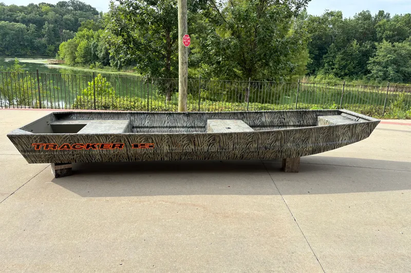The Image of 2027 Tracker Grizzly 15 Jon boat with camouflage design, parked near a scenic lake. - 0